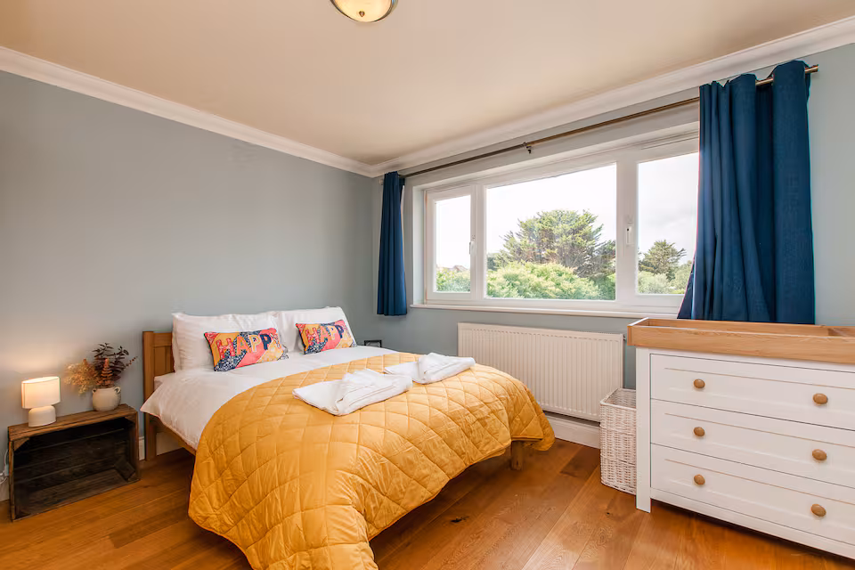 Bright double bedroom with colourful cushions and woodland view