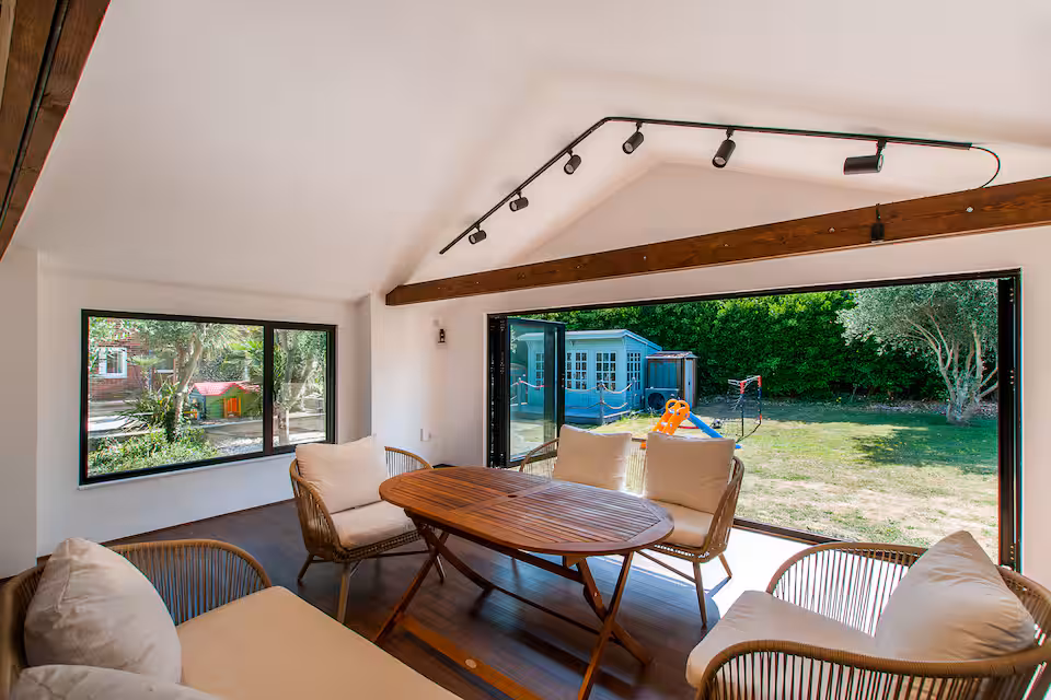 Garden room with bifold doors, dining table and rattan seating
