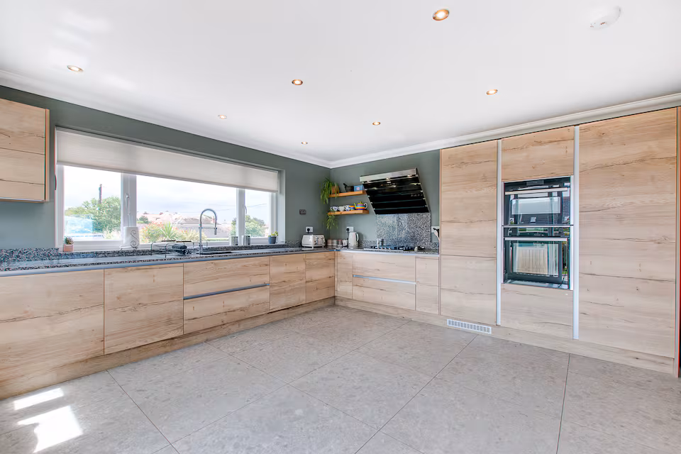 Fully fitted modern kitchen with integrated appliances and garden view