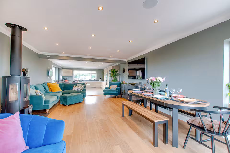 Open-plan living and dining with log burner, set table and wall-mounted TV