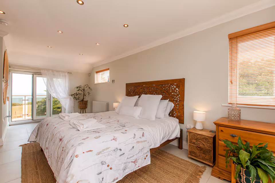 Master suite with carved wooden bed, sea-view balcony and indoor plants