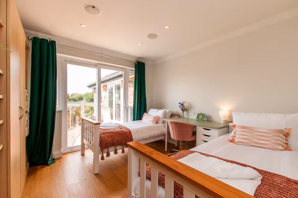 Twin bedroom with workspace, balcony access and terracotta accents